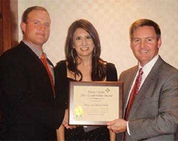 Adam and Michele Holk are pictured with Farm Credit Bank of Texas Chief Administrative Officer Stan Ray, right.
